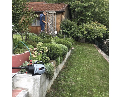 Gartenbewässerung mit Gartenpumpe vor einem Haus
