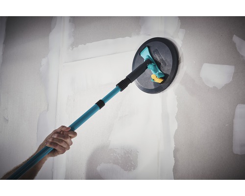 Eine Person glättet eine Wand mit einem Deckenschleifer mit Teleskopstiel.