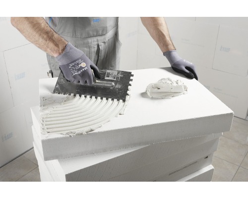 Anwendung von Kleber auf eine Porenbetonplatte mit einer Glättkelle