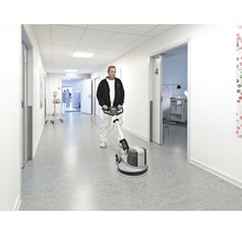 Eine Person reinigt einen Flur mit einer Reinigungsmaschine.
