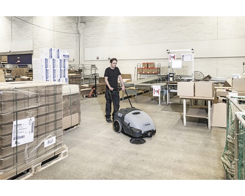 Mann bedient Kehrmaschine in Lagerhalle