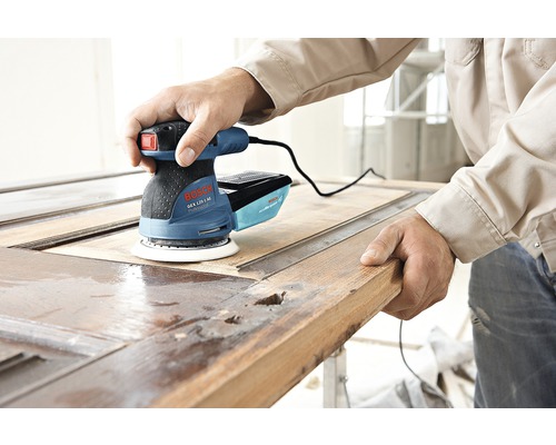 Ein Mann verwendet einen Bosch Exzenterschleifer zum Schleifen einer Holztür.