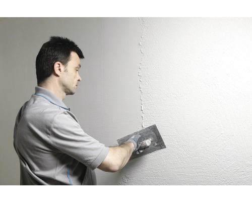 Mann glättet Wand mit Spachtel