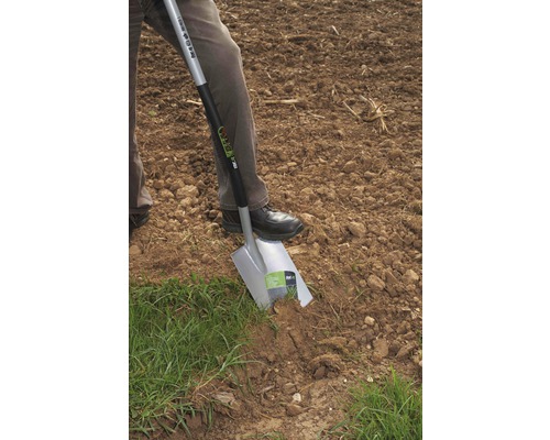 Person sticht Spaten in den Boden auf einem Feld.