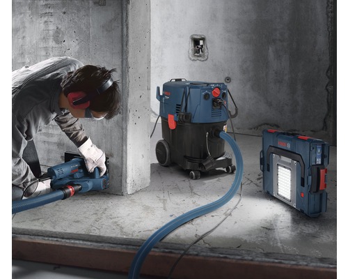 Anwendungsszene mit Mauernutfräse, Industriestaubsauger und Akku-Baustrahler auf einer Baustelle