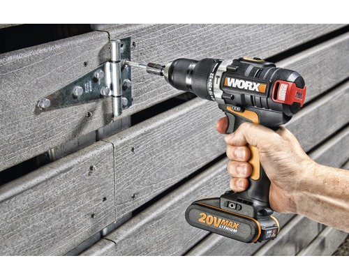 Akkuschrauber beim Anbringen eines Scharniers an einem Holzzaun