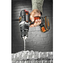 Eine Hand hält einen Worx Akku-Bohrschrauber, der durch einen Ziegelstein bohrt.