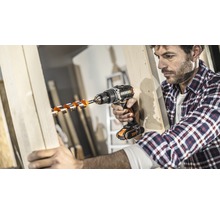 Mann bohrt mit einem Akkubohrer ein Loch in ein Holzbrett.