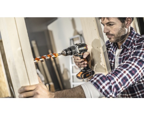 Mann bohrt mit einem Akkubohrer ein Loch in ein Holzbrett.