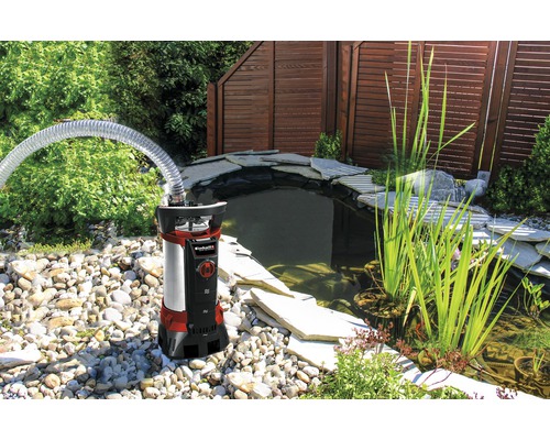 Teichpumpe mit Schlauch neben einem Teich