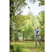 Mann benutzt eine Hochentaster im Garten, um Äste von einem Baum zu schneiden.