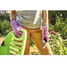 Frau mit Gartenhandschuhen, Gartenschere und Schubkarre im Garten.
