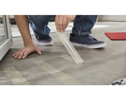 Eine Person befestigt Glasfasergewebeband auf einem Boden.