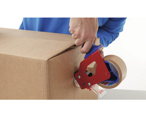 Eine Person verschließt einen Karton mit einem Klebebandabroller.