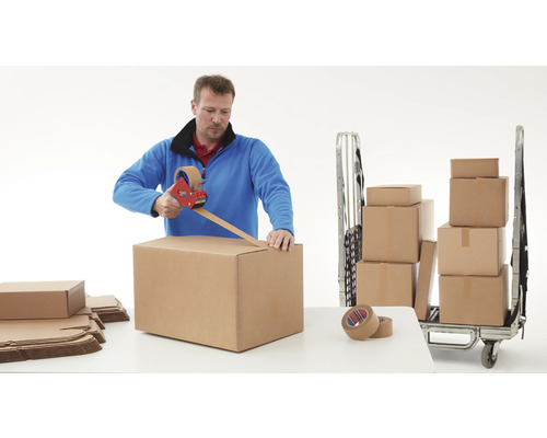 Mann verpackt Umzugskarton mit Klebebandabroller. Ein Rollwagen mit Umzugskartons steht bereit.