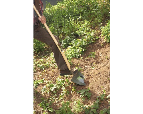 Eine Person benutzt einen Spaten zum Umgraben von Erde im Garten.