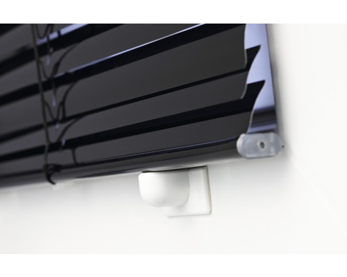 Detailansicht einer schwarzen Jalousie an einer Wand.