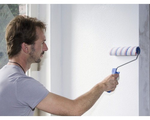 Mann streicht eine Wand mit einer Farbwalze