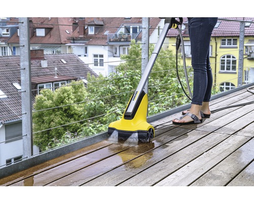 Frau reinigt Holzterrasse mit Kärcher Terrassenreiniger