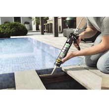 Handwerker verwendet Klebstoff aus einer Kartusche zum Verkleben eines Holzdecks neben einem Pool.