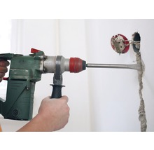 Bohrmaschine mit Meißel, die eine Wand bearbeitet