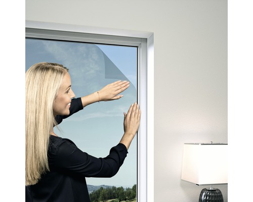 Fliegengitter Windhager Elastic PLUS für Fenster ohne Bohren anthrazit 130x150 cm Frau bringt Fensterfolie an einem Fenster an