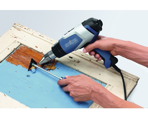 Farbe wird mit einem Heißluftfön und einem Spachtel von einem Holzrahmen entfernt