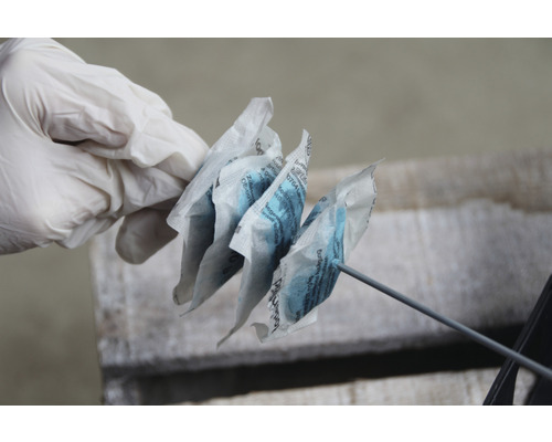 Eine Hand mit Handschuh hält mehrere Beutel mit Feuchtigkeitsspeichergranulat.