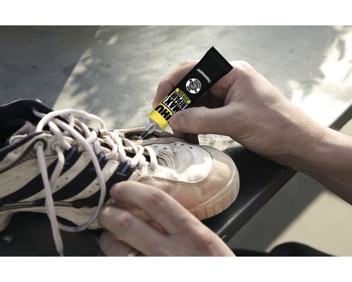 Eine Person repariert einen Schuh mit Schuhkleber.