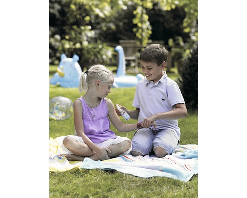 Junge sprüht Insektenschutzmittel auf den Arm eines Mädchens im Garten.