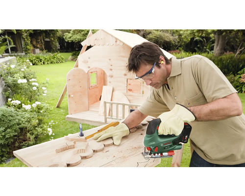 Mann sägt Holz mit Stichsäge für ein Holzhaus