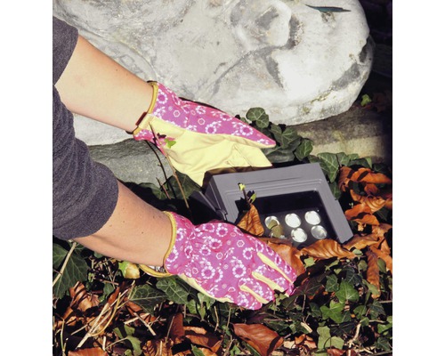 Gartenarbeit mit Gartenhandschuhen und einer Gartenleuchte.