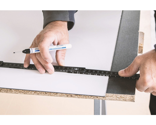 Eine Person markiert eine Platte mit einem Stift und einem Zollstock.
