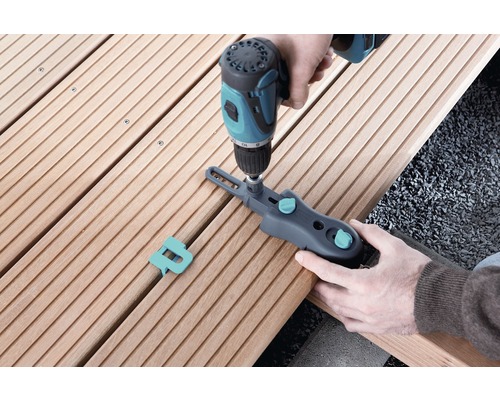 Person befestigt Terrassendiele mit Schraubzwinge und Akkuschrauber