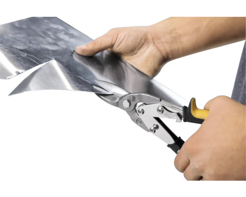 Eine Person schneidet ein Blech mit einer Blechschere.