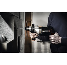 Eine Person bohrt mit einem Akku-Bohrhammer in eine Ziegelwand. Zu sehen ist der Worx Logo.