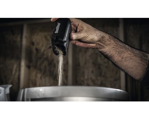 Eine Hand schüttet Staub aus einem DustStop Staubbehälter.