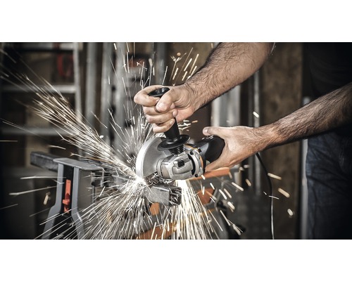 Eine Person schneidet Metall mit einem Winkelschleifer, wobei Funken entstehen.