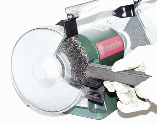 Metabo Tischschleifmaschine mit Drahtbürste beim Entrosten eines Metallstücks