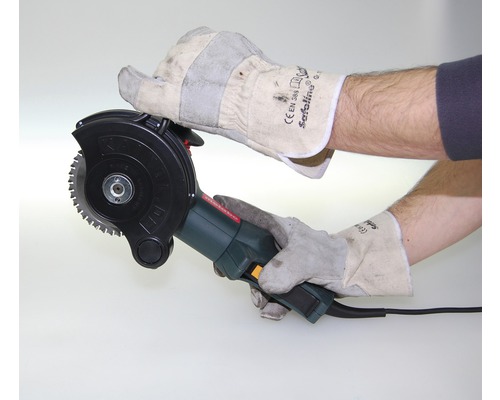 Mann mit Schutzhandschuhen bedient eine Mauernutfräse.