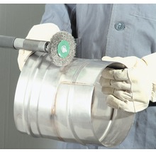Eine Person verwendet eine Drahtbürste an einem Metallrohr zur Reinigung.