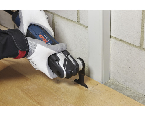 Eine Person benutzt ein Multifunktionswerkzeug von Bosch zum Schneiden von Holz.