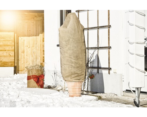 Pflanztopf mit Winterschutzhülle im verschneiten Garten