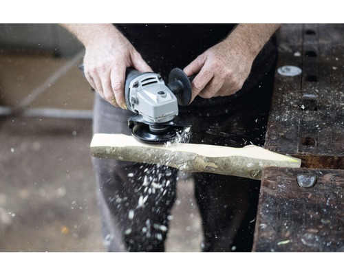 Eine Person schleift ein Stück Holz mit einem Winkelschleifer.