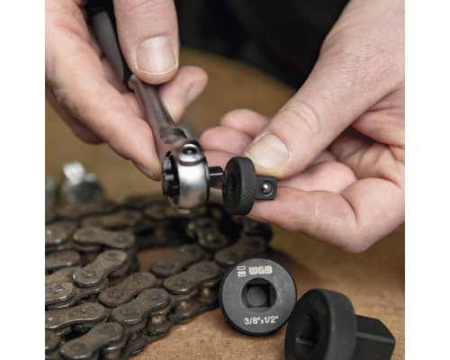 Person verbindet Ratsche mit Steckschlüsseleinsatz neben einer Fahrradkette