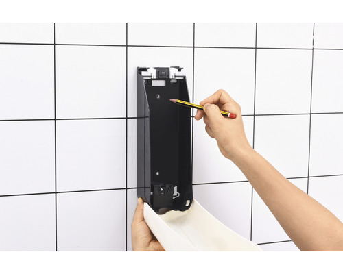 Montage eines Seifenspenders an einer gefliessten Wand mit Bleistiftmarkierung.