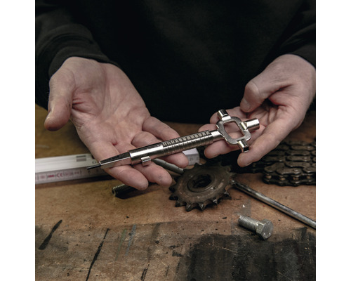 Eine Person hält ein Kettenverschleißwerkzeug aus Metall für Fahrräder in den Händen