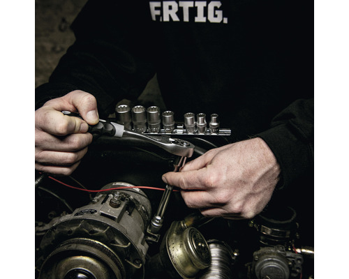 Eine Person benutzt einen Ratschenschlüssel und Steckschlüssel für Reparaturen an einem Automotor.