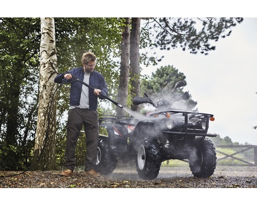 Mann reinigt Quad mit Hochdruckreiniger im Freien