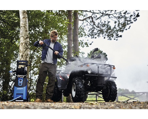 Mann reinigt Quad mit Hochdruckreiniger im Freien.